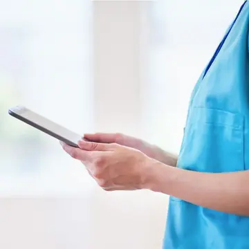 Foto: iStock | Meeko Media Eine Pflegerin hält ein Tablet